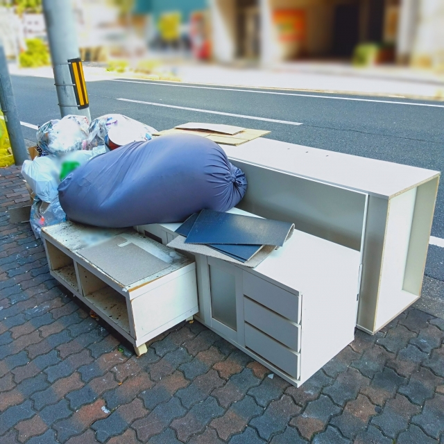 歩道に出された不用品（白い棚・袋・段ボール）